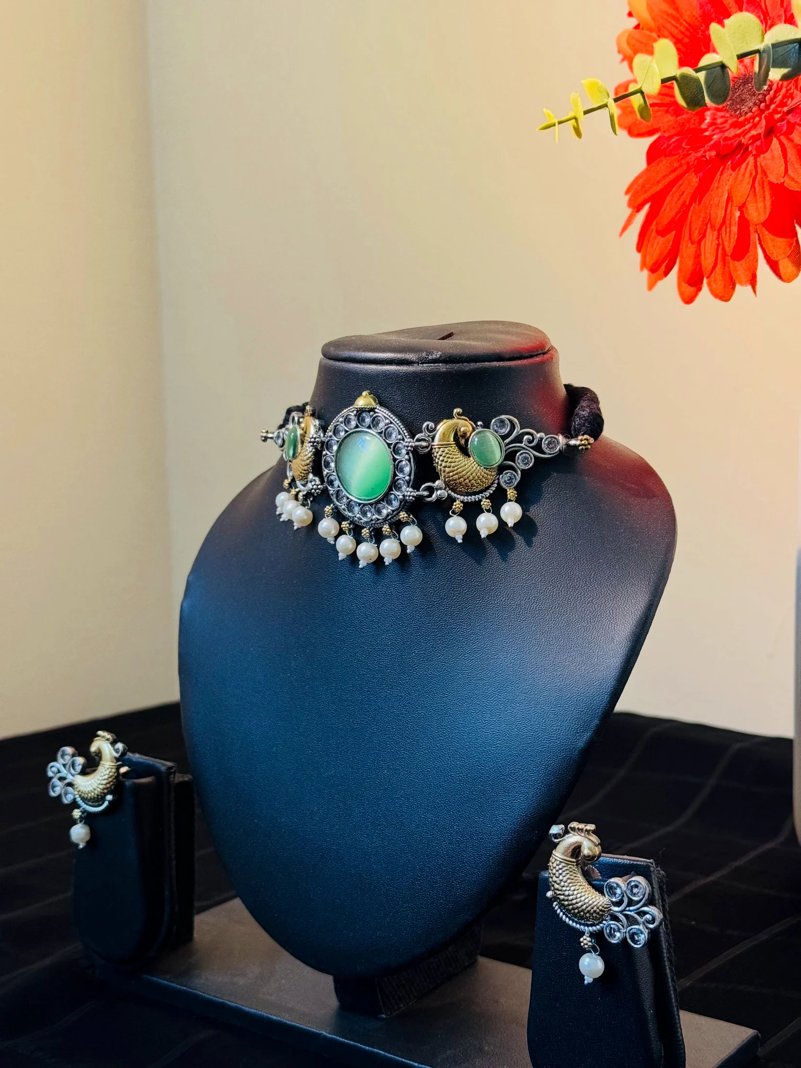 Alankara peacock choker and matching earrings displayed on black stands